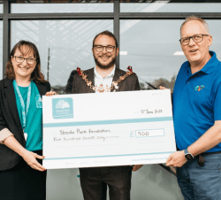 Two people holding a giant cheque, with the Mayor of Faversham standing in the middle.