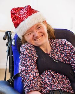 Smiling young lady wearing a santa hat sitting in a wheelchair