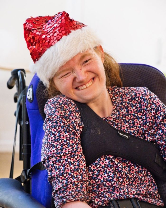 Smiling young lady wearing a santa hat sitting in a wheelchair