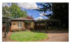 Bungalow with green grass in the front and tree