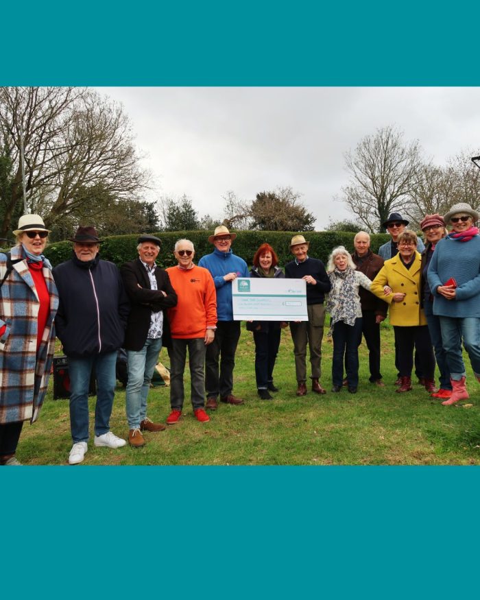 Group of people standing on grass holding a giant cheque
