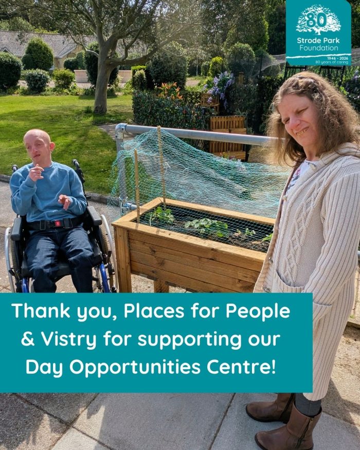 Male in wheelchair and female standing in garden next to high rise planter